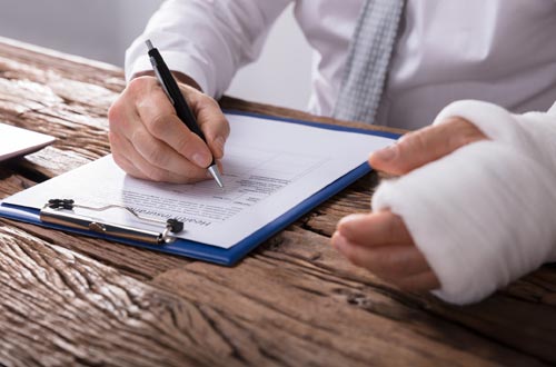 Workers Insurance — Man with Broken Arm Signing a Form in Gallup, NM