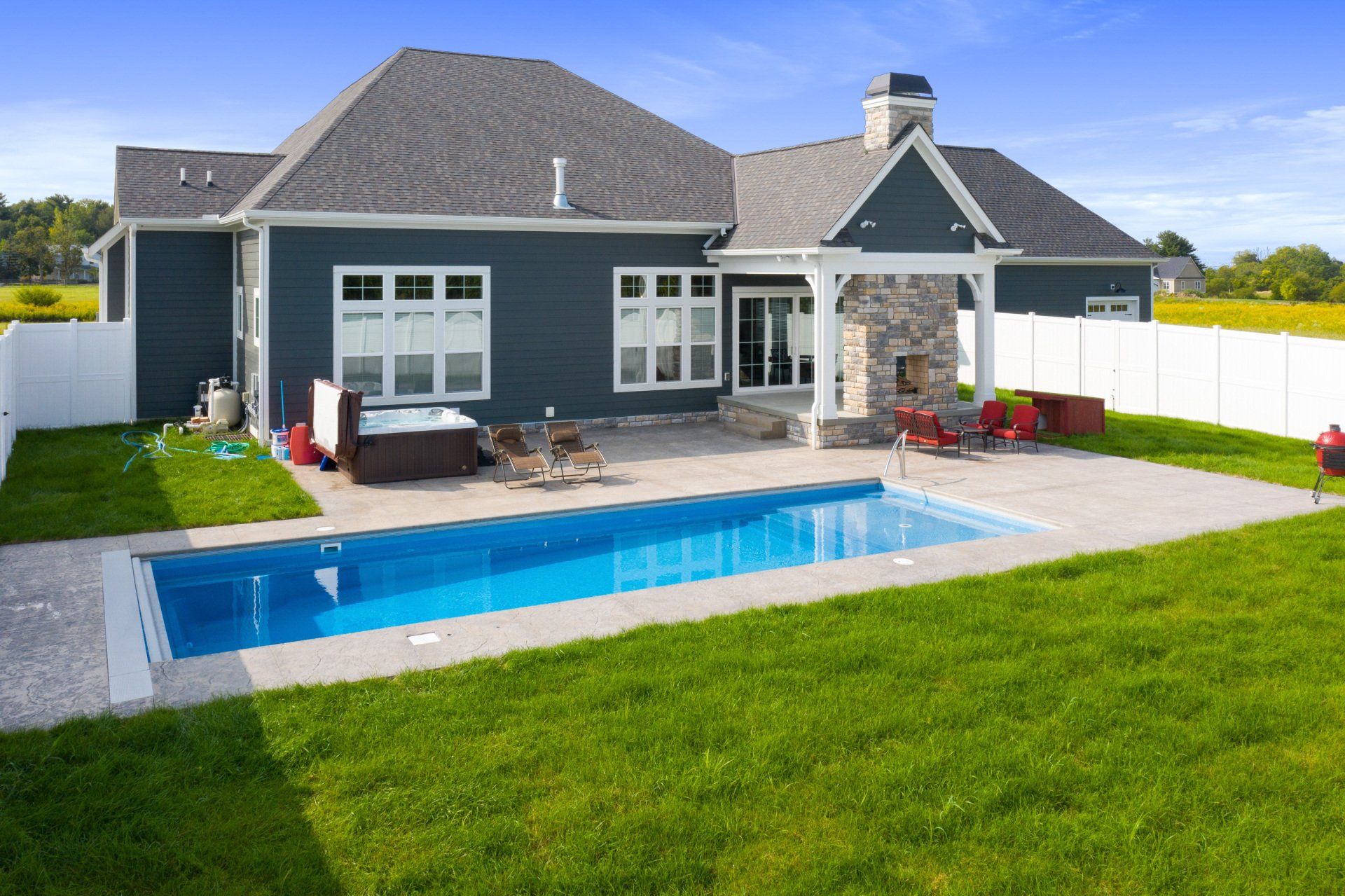 Modern house with a backyard pool, patio seating, and a green lawn