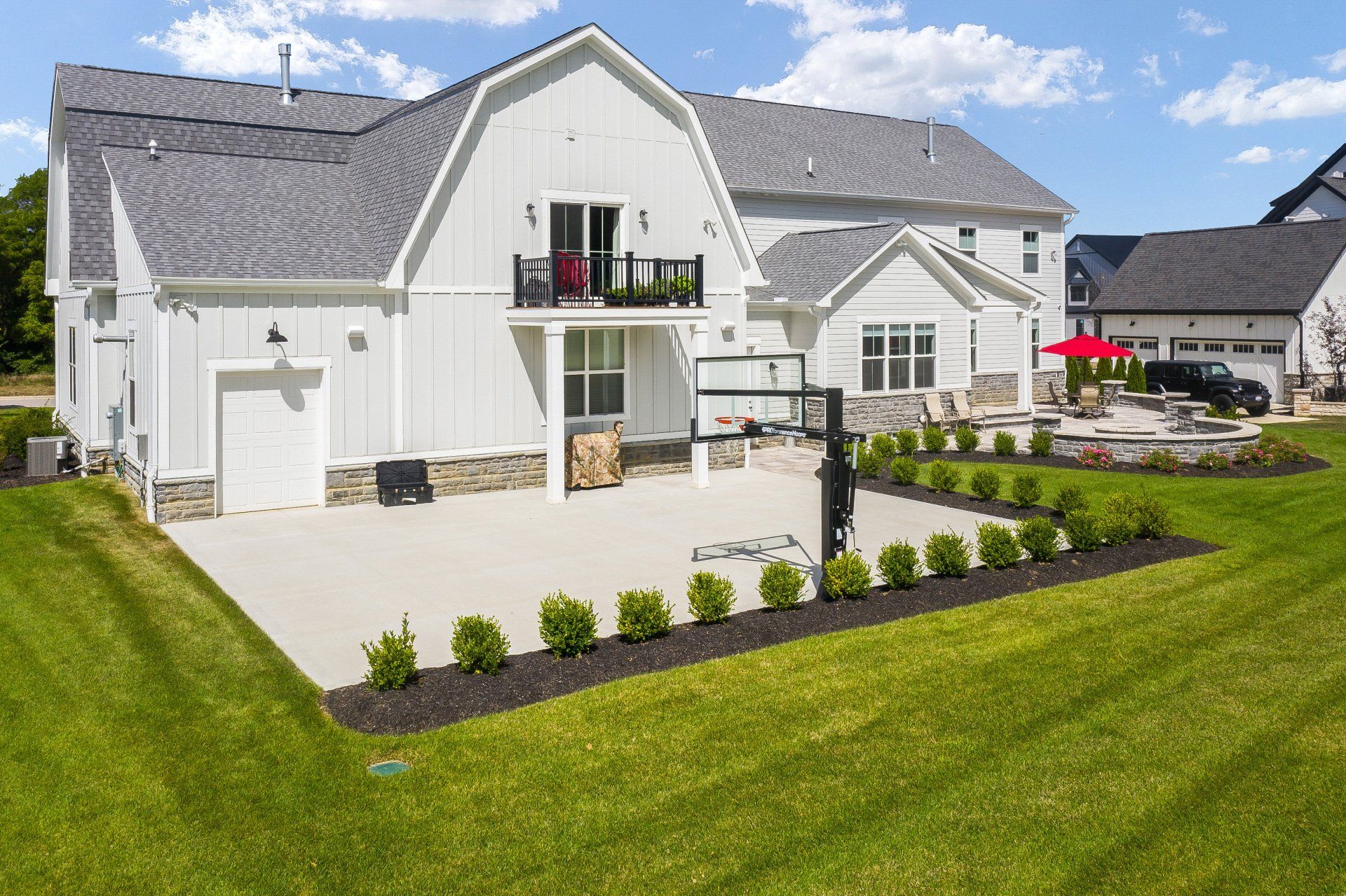 Modern white house with balcony, patio, and landscaped green lawn on a sunny day