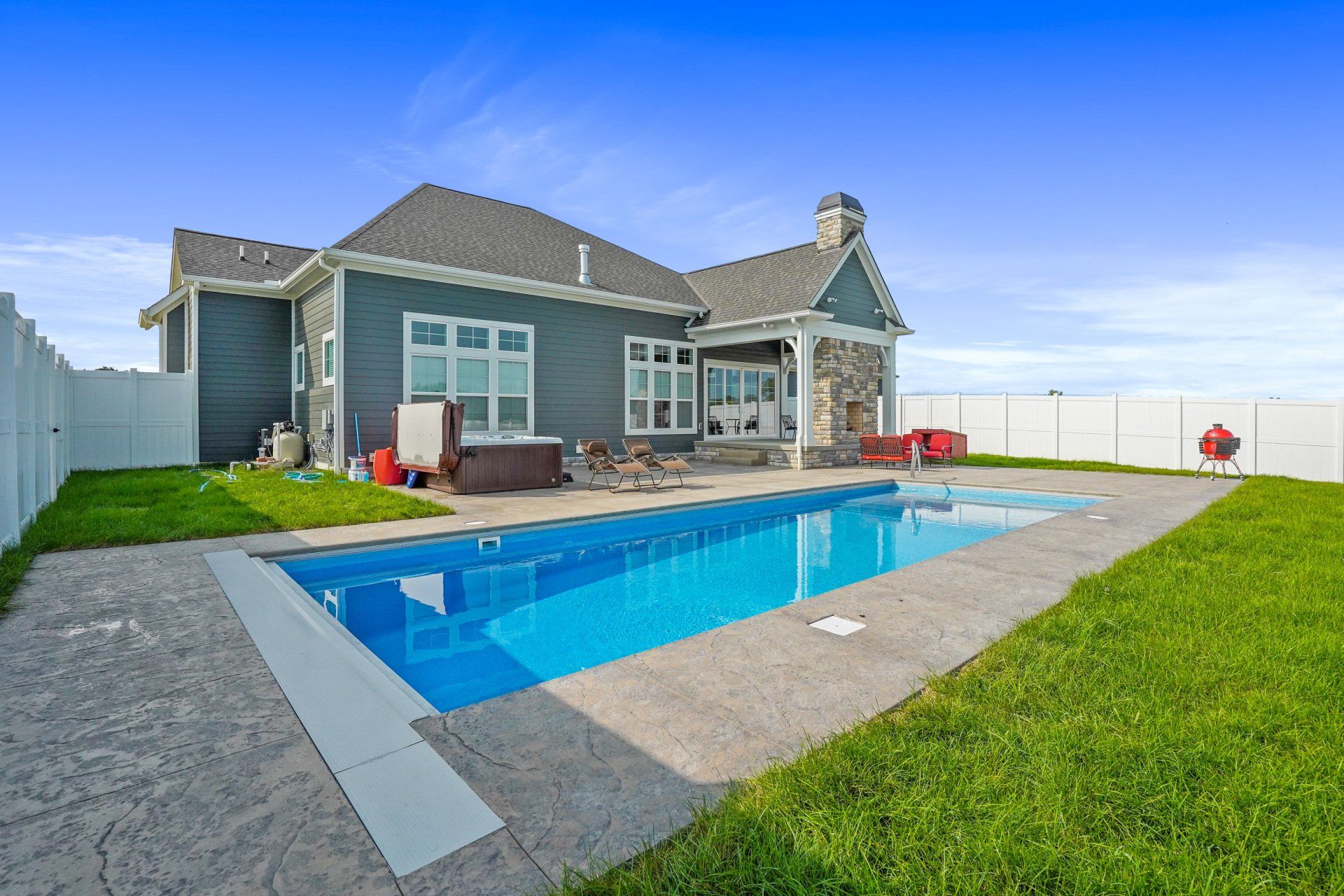 Backyard with a modern house and a rectangular blue swimming pool beside a green lawn