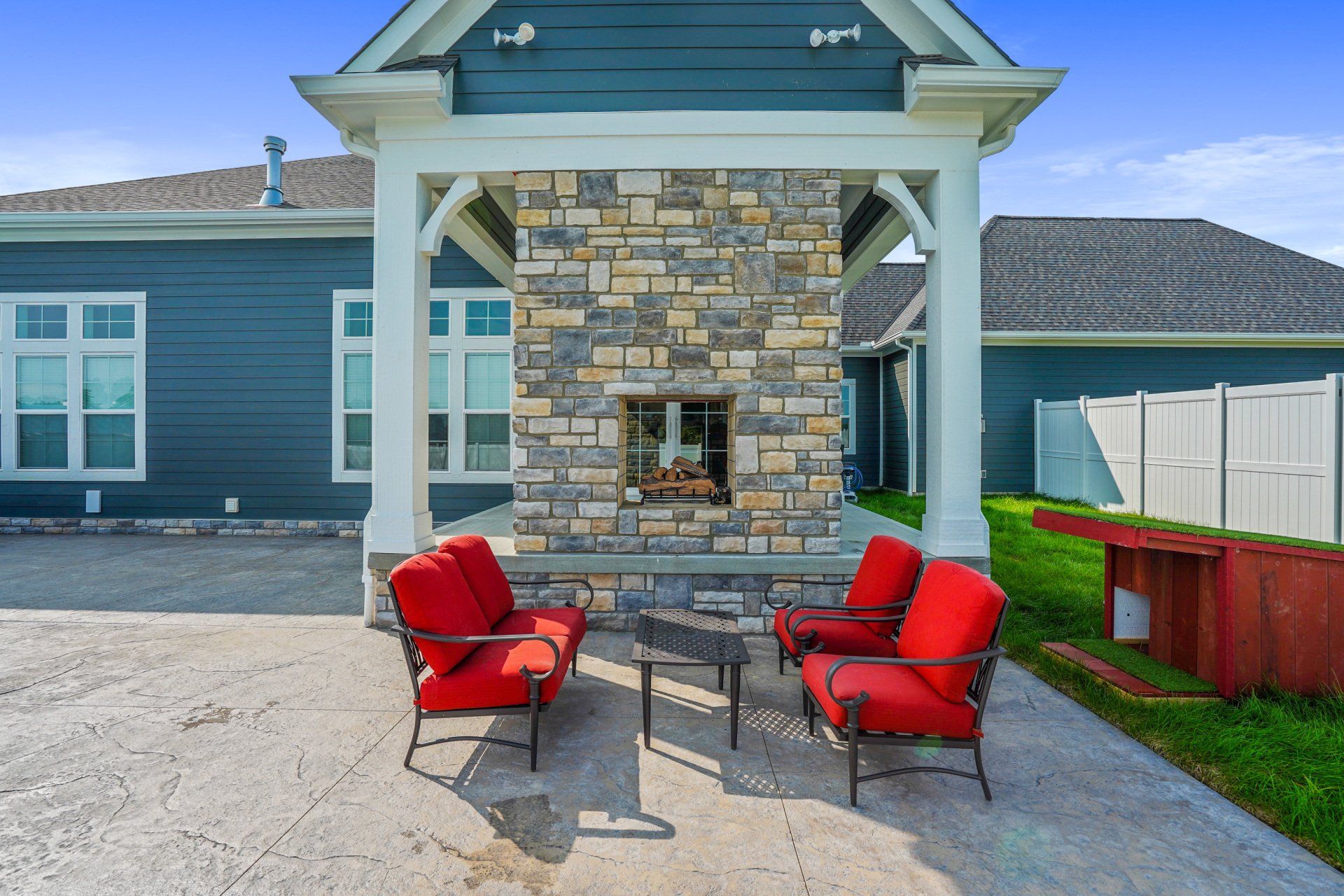 Outdoor patio with red chairs and a table beside a stone fireplace on a porch