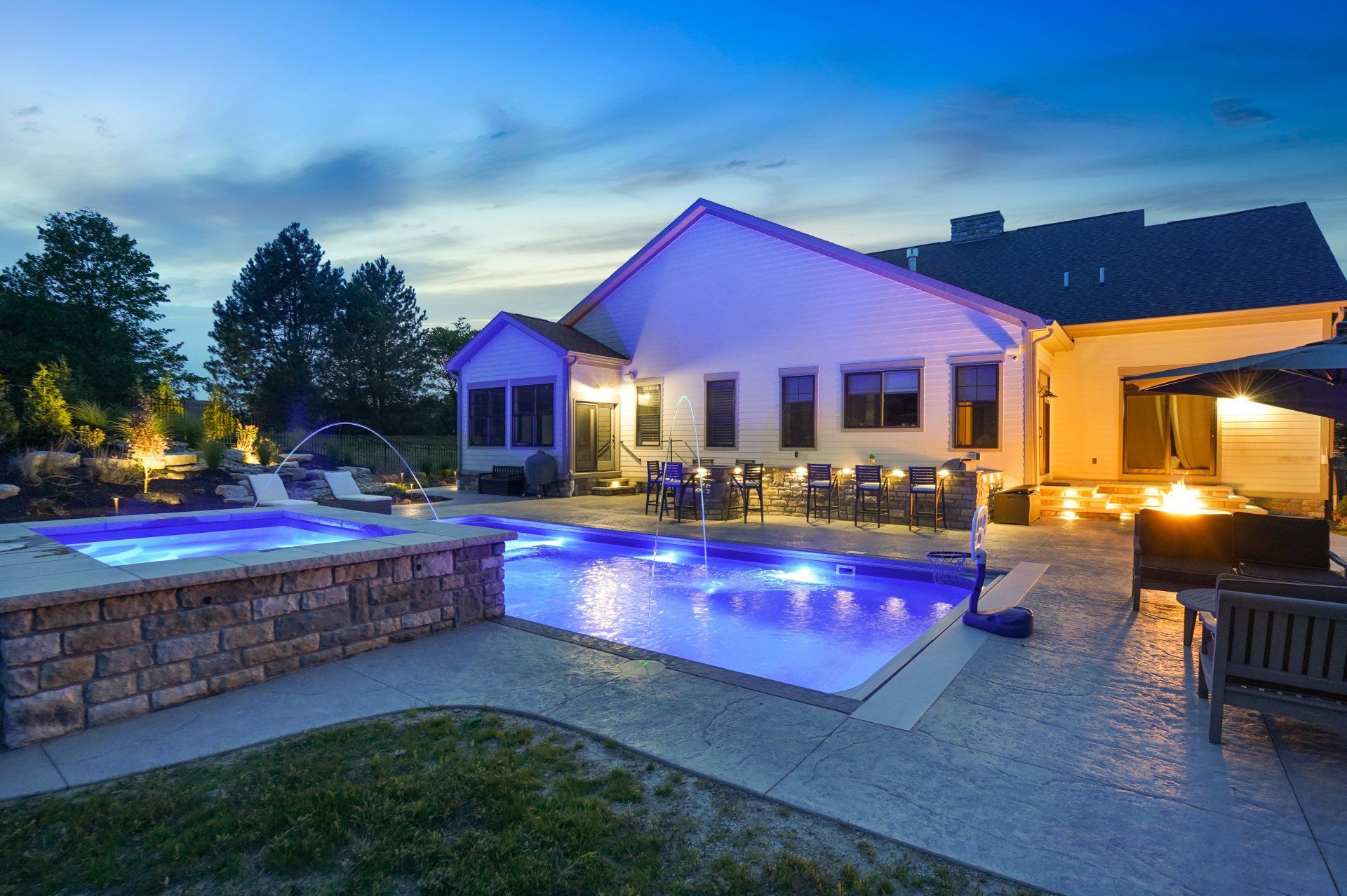 Lit modern house with illuminated pool and patio at dusk