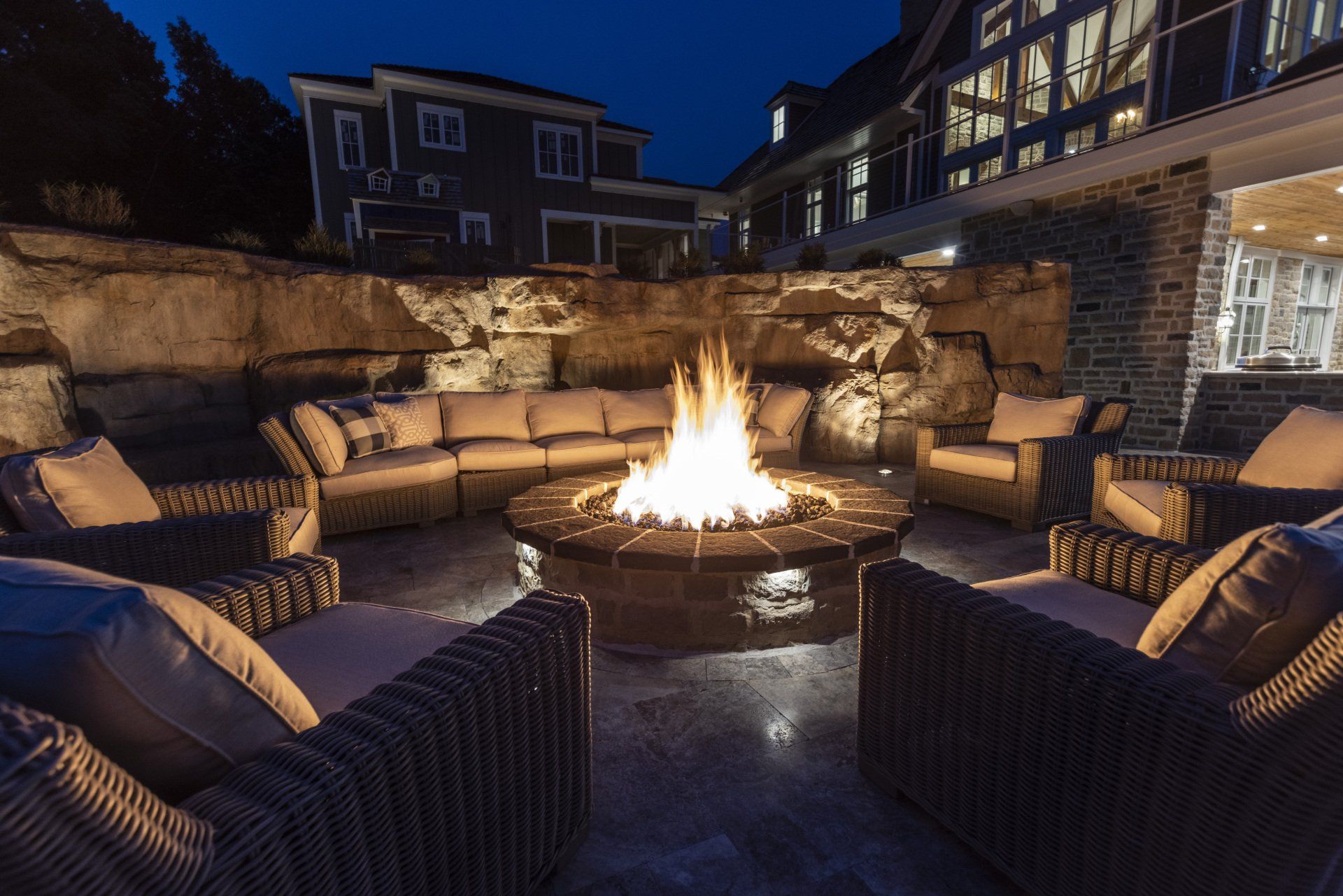 Cozy outdoor patio with wicker seating around a lit fire pit at dusk