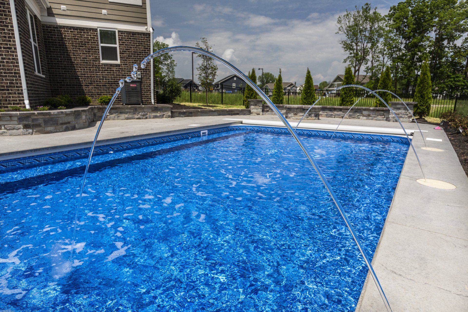 Backyard swimming pool with a hose spraying water into bright blue water