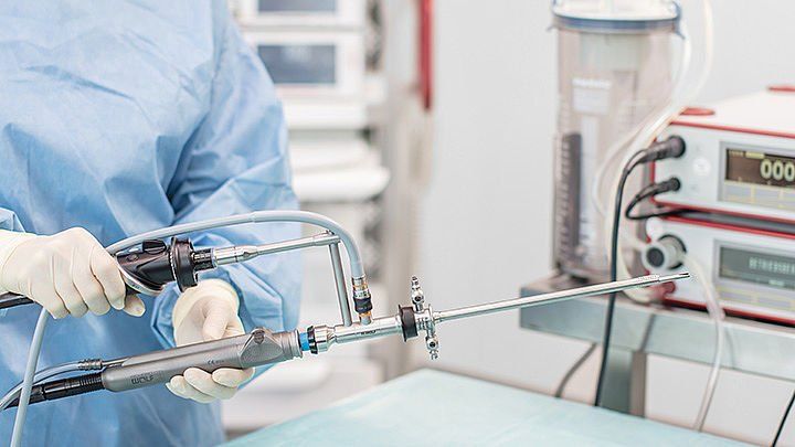 A surgeon is holding a surgical instrument in an operating room.