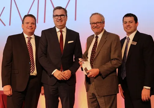 Four men in suits and ties are posing for a picture