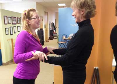 A woman in a purple shirt is talking to another woman in a black shirt.