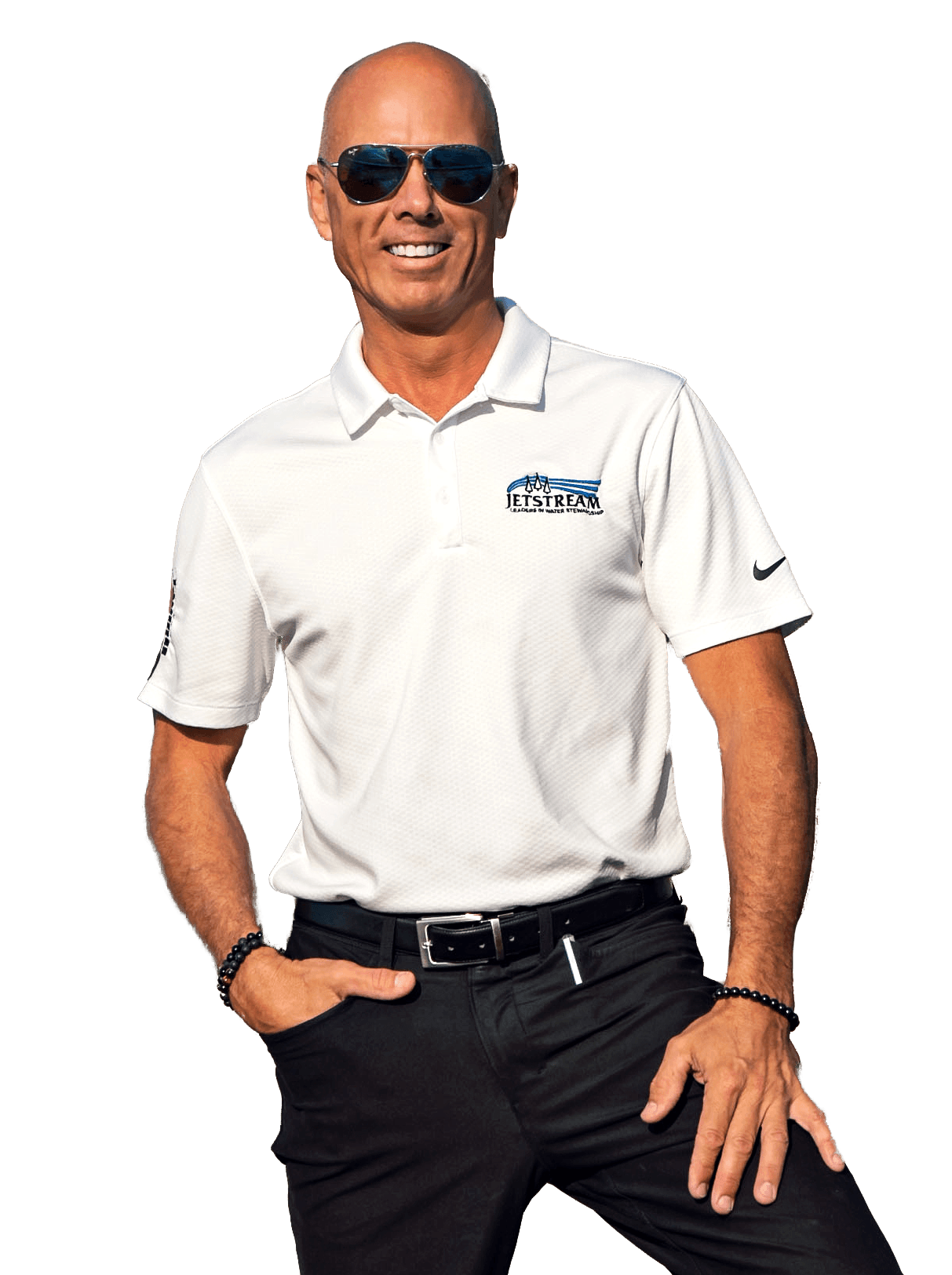 A man wearing sunglasses and a white polo shirt is standing with his hands in his pockets.