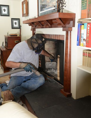 Man on top of a room cleaning a chimney