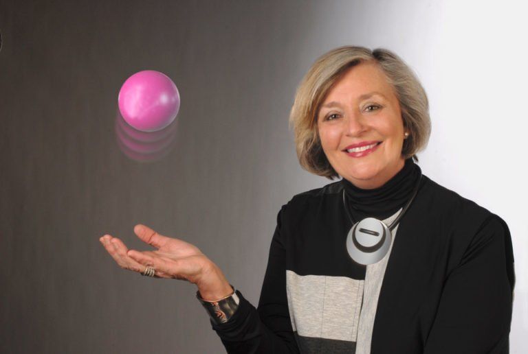 A woman is holding a pink ball in her hand