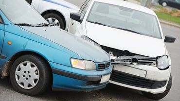 Ein blaues und ein weißes Auto sind in einen Autounfall verwickelt.