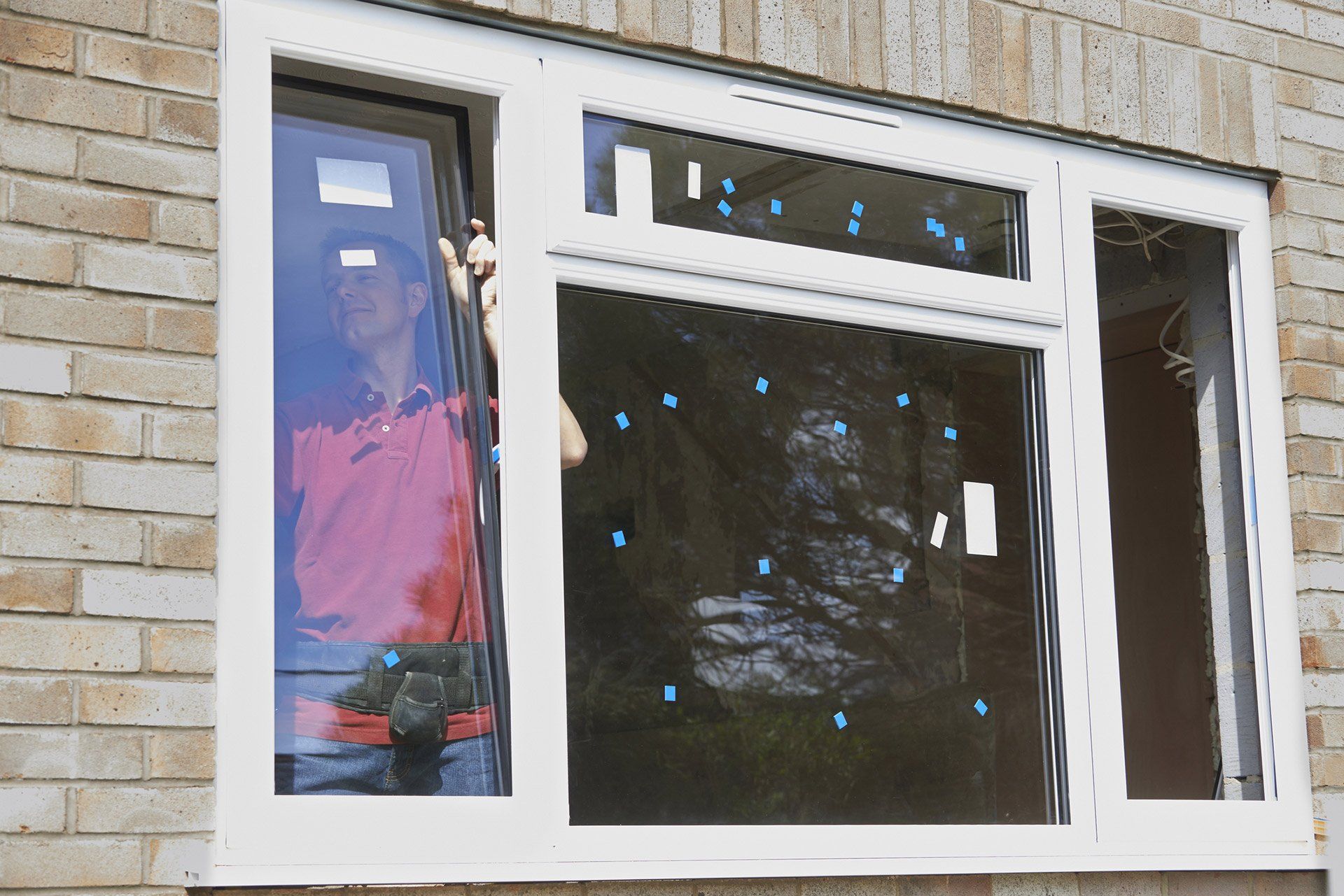 a man in a red shirt is working on a window