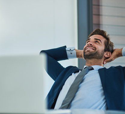 uomo in abito formale mette le braccia dietro alla testa