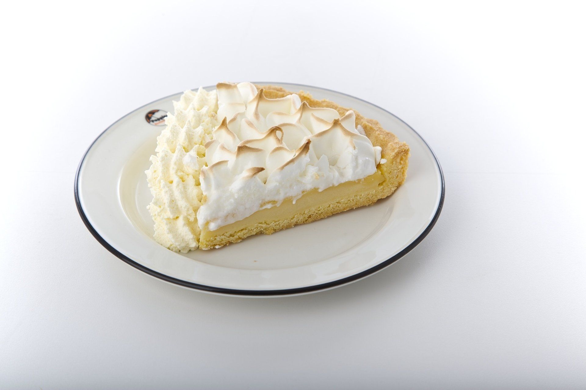 Slice of white meringue pie with whipped topping on a white plate.
