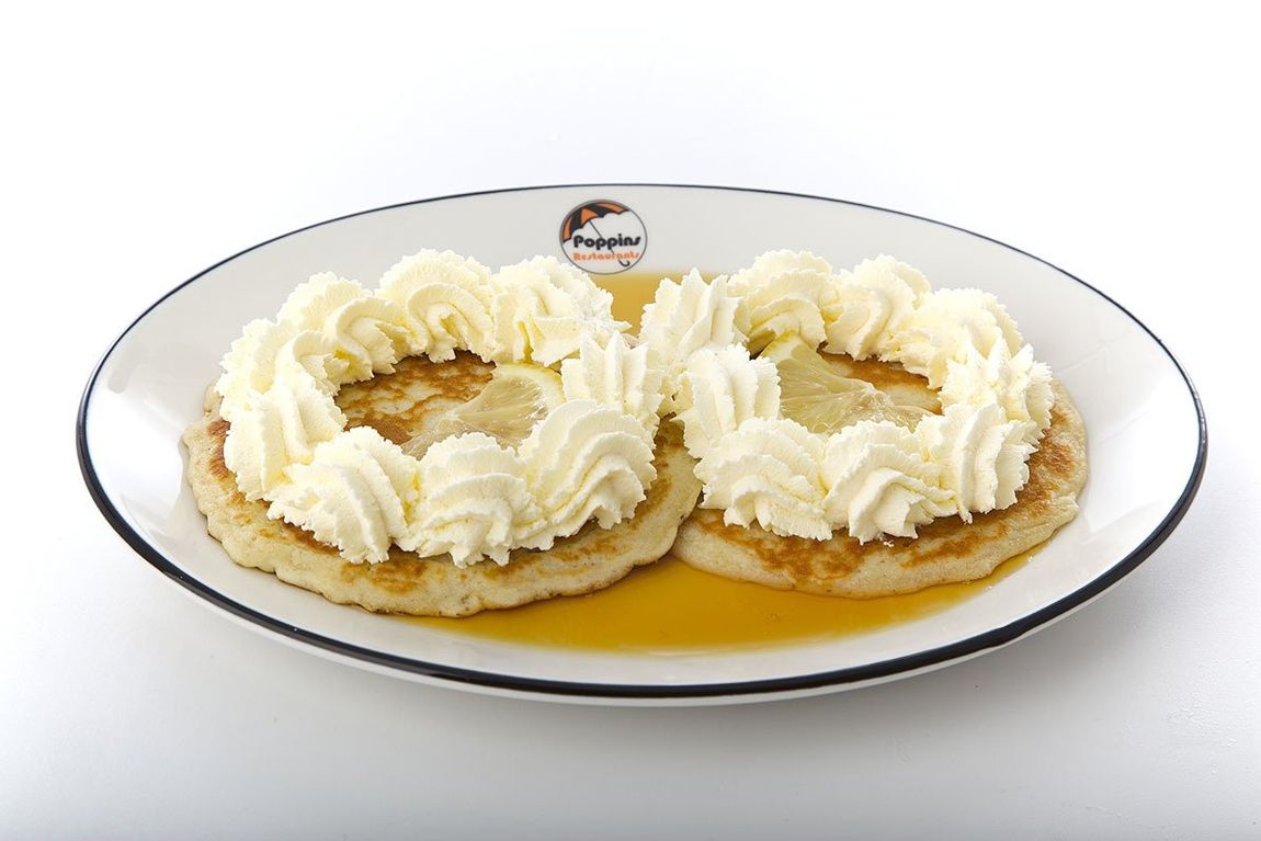 Two cream-topped pastries on a white plate with caramel sauce