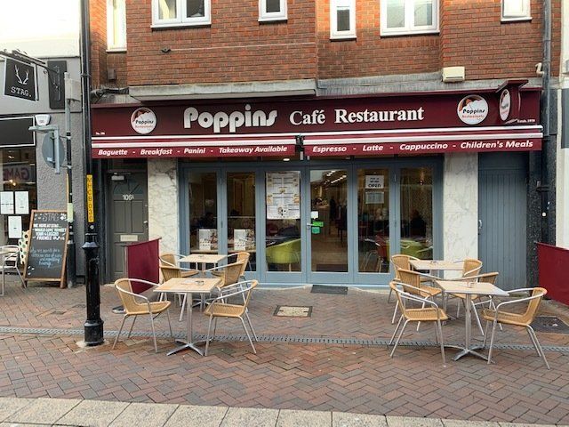 Poppin Café Restaurant storefront with outdoor tables and chairs on a brick sidewalk