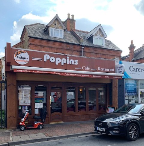 Poppins Café restaurant storefront with brown awning, parked scooter, and black car on the street