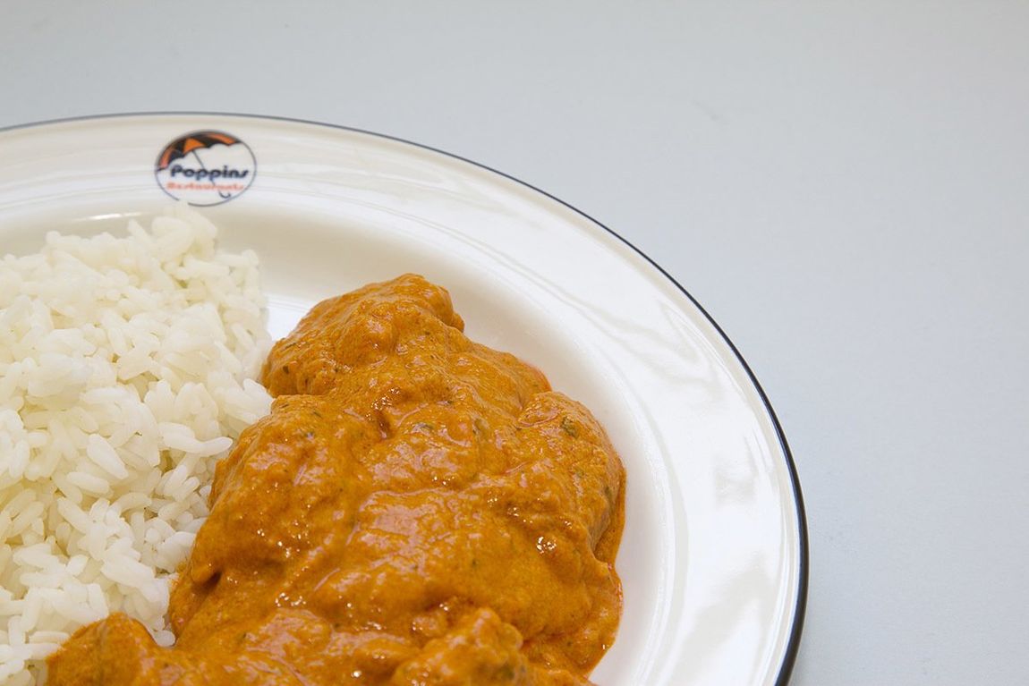 Plate of white rice and orange curry on a white dish