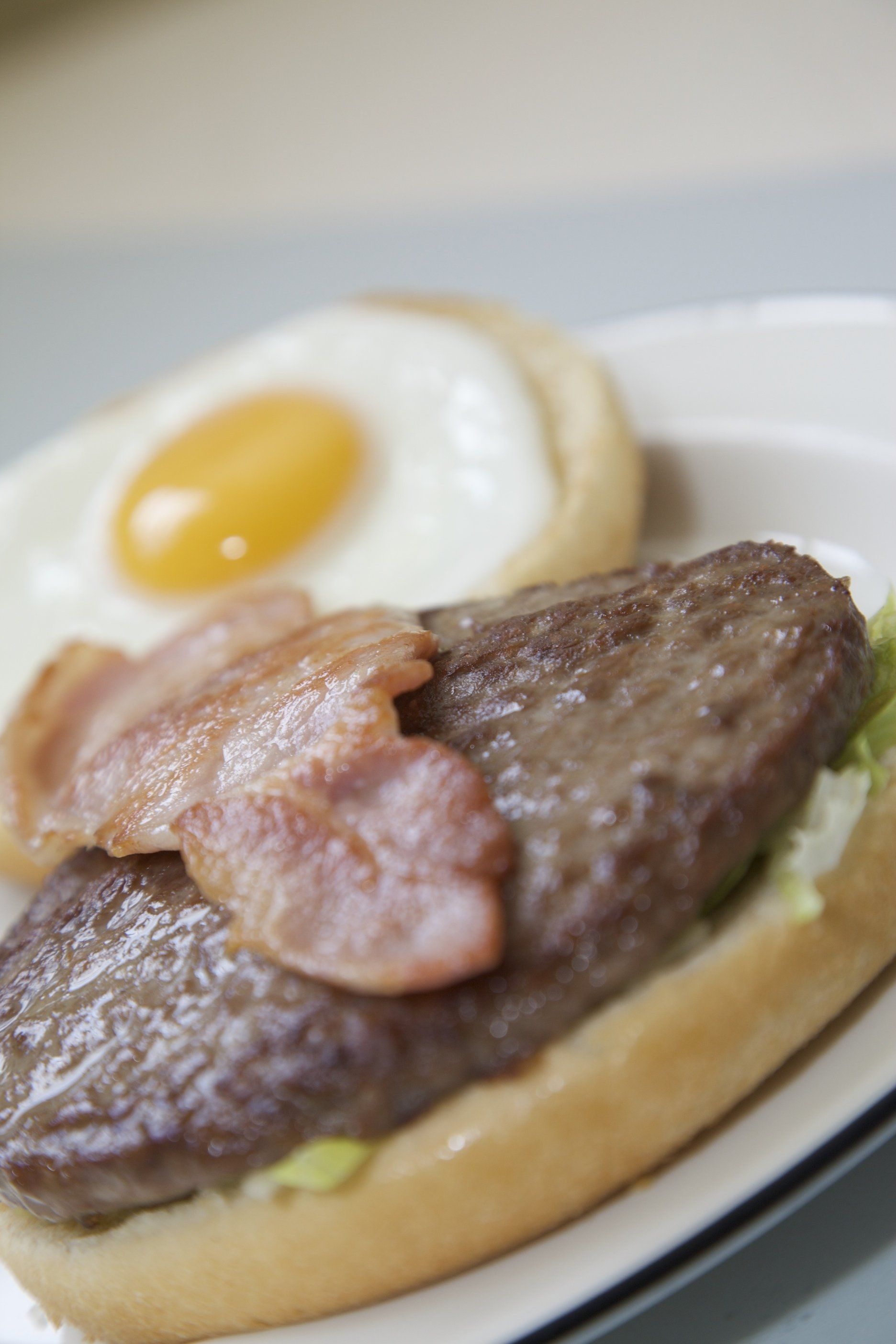 Breakfast sandwich with fried egg and bacon on a toasted bun