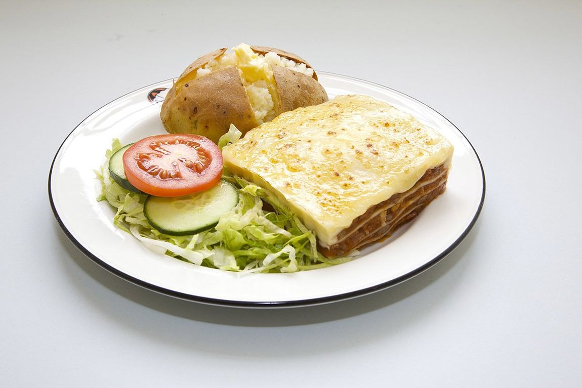 Plated sandwich with lettuce, tomato, and potato wedges on a white dish