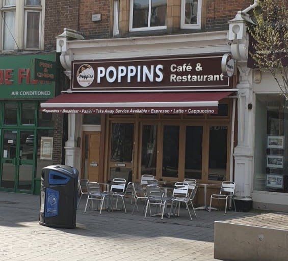 Poppins Café & Restaurant storefront with outdoor seating and a blue trash bin on the sidewalk