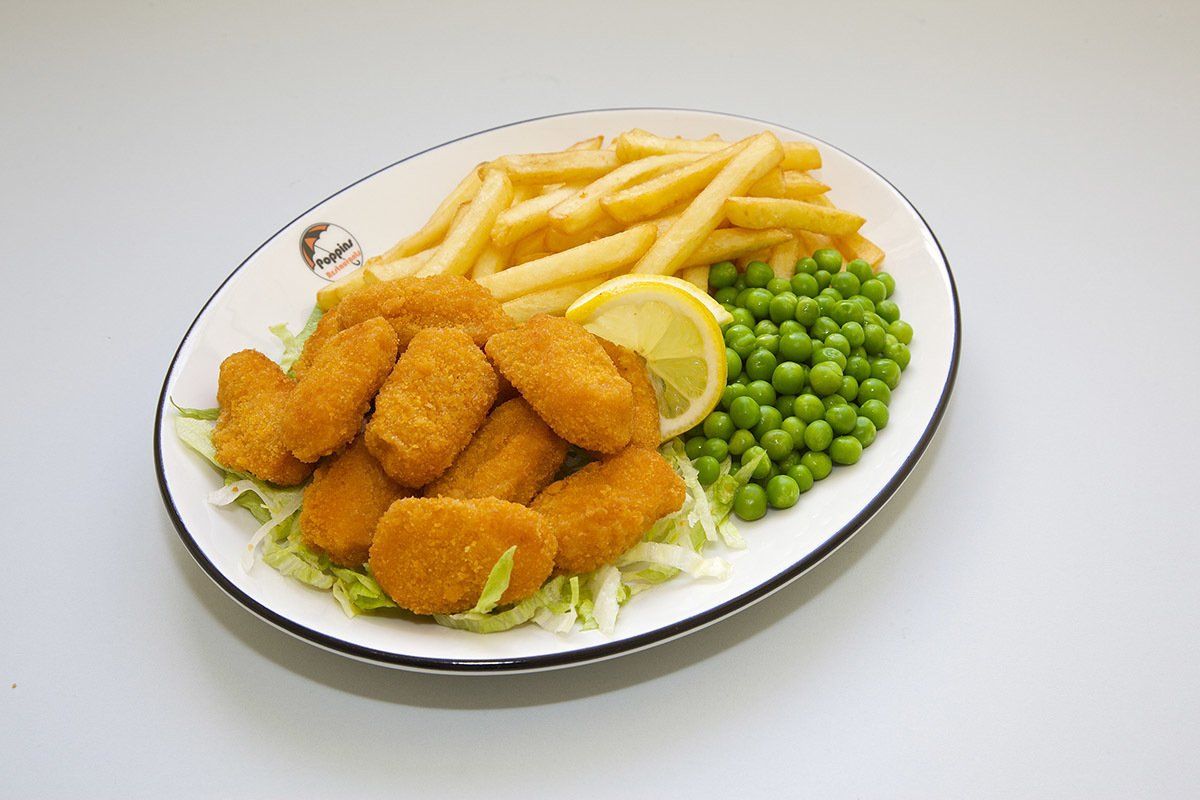 Breaded fish fillets with fries, peas, and lemon wedges on a white plate