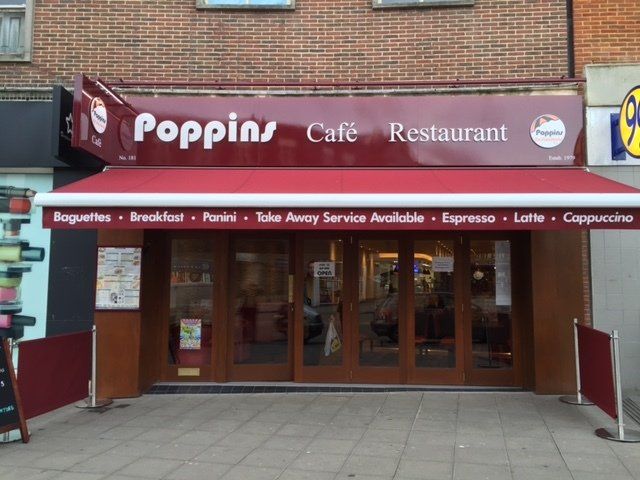 Poppins Café Restaurant storefront with maroon awning and red sign on a brick building