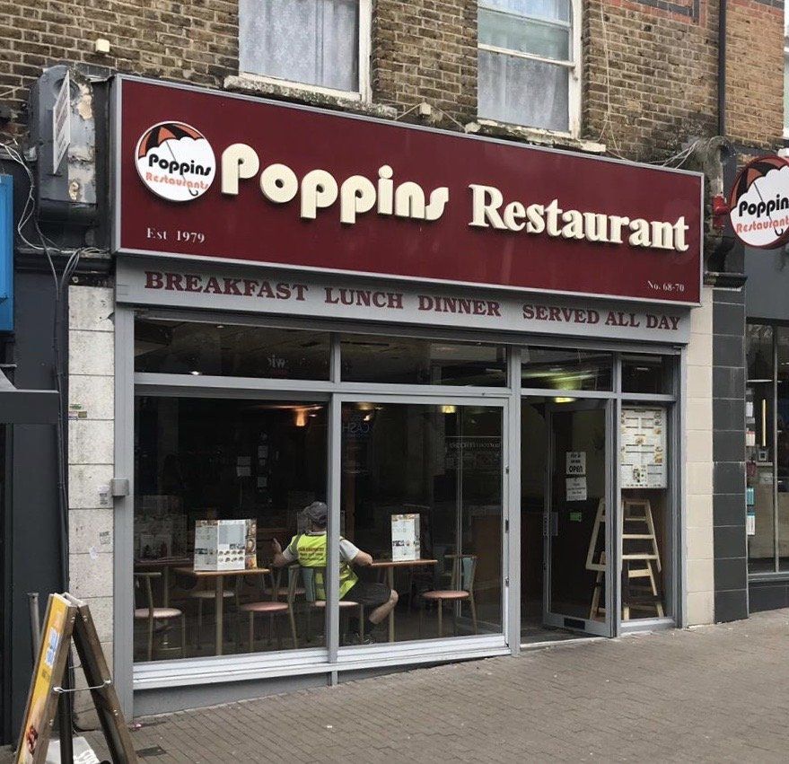 Peppino Restaurant storefront with red sign, glass entrance, and outdoor seating on a city street.