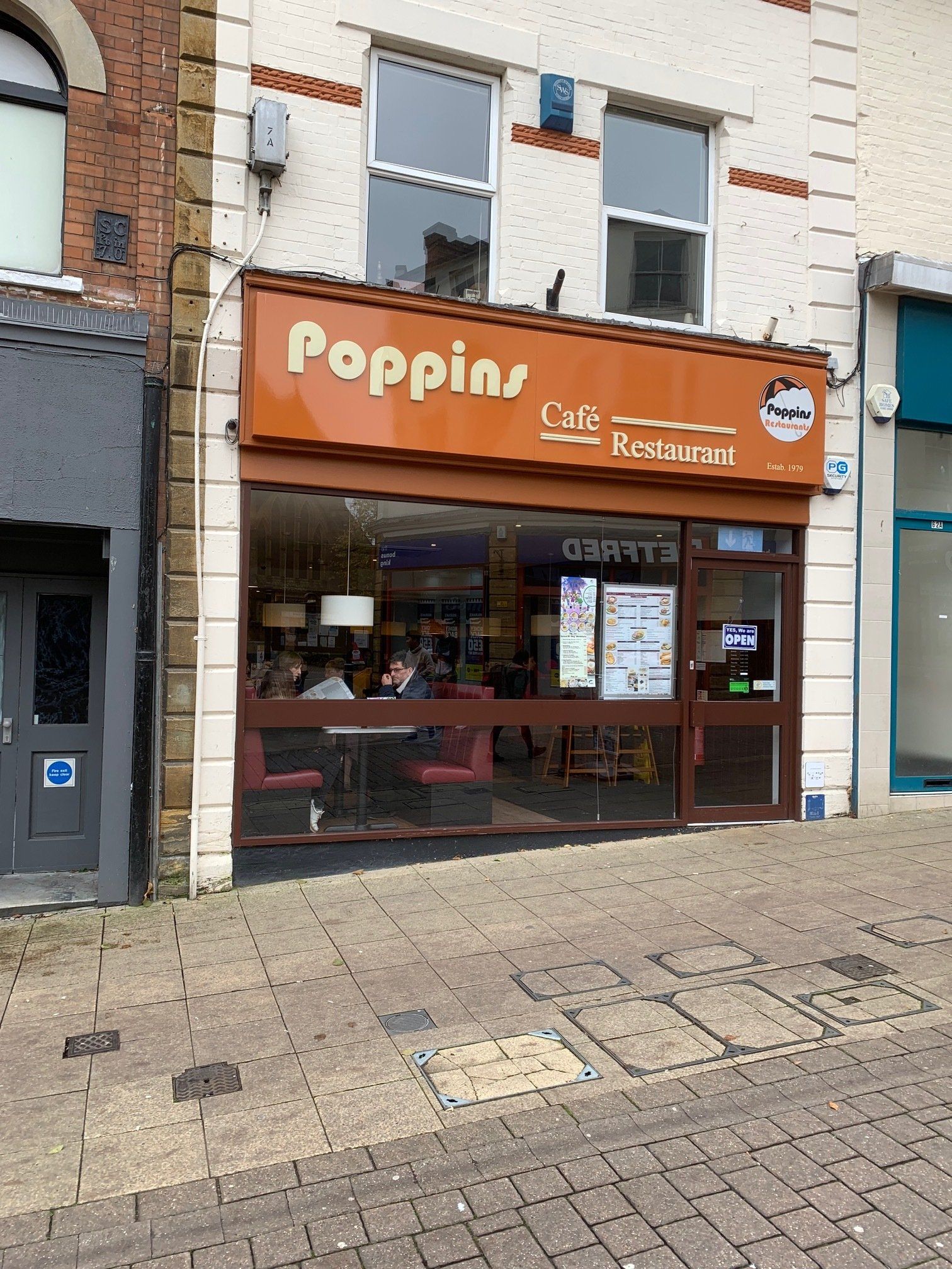 Poppin café storefront with orange sign and glass windows on a city street
