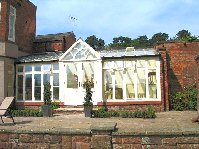 Sunroom attached to a brick building with a paved patio.
