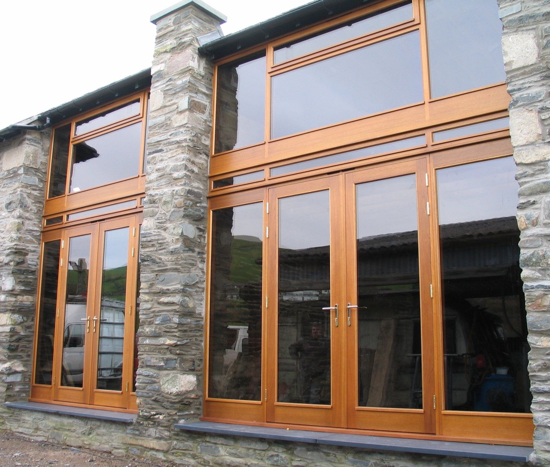Stone building with large wooden-framed windows and doors.
