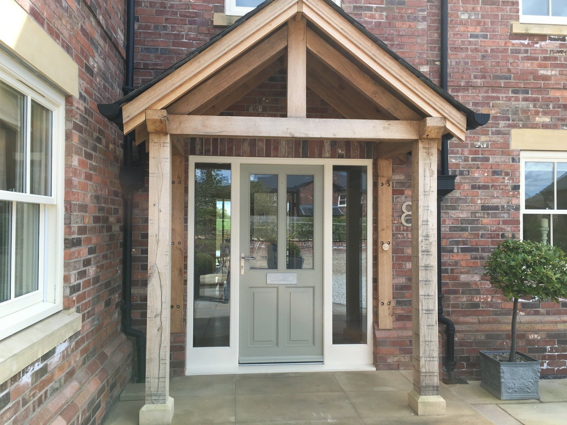 Brick house entrance with a wooden porch and gray door.