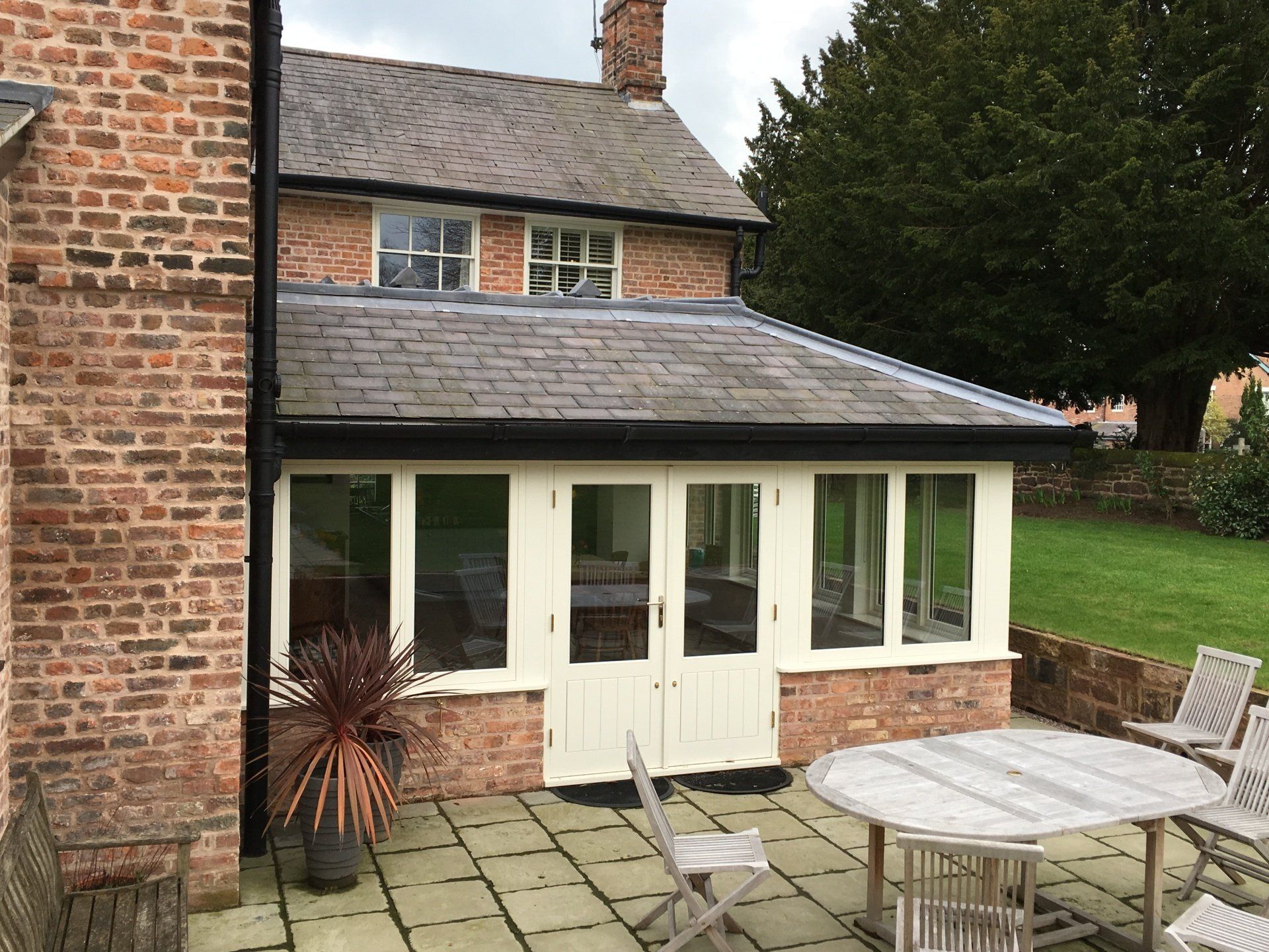 Brick house with a patio and a sunroom with white trim and French doors.