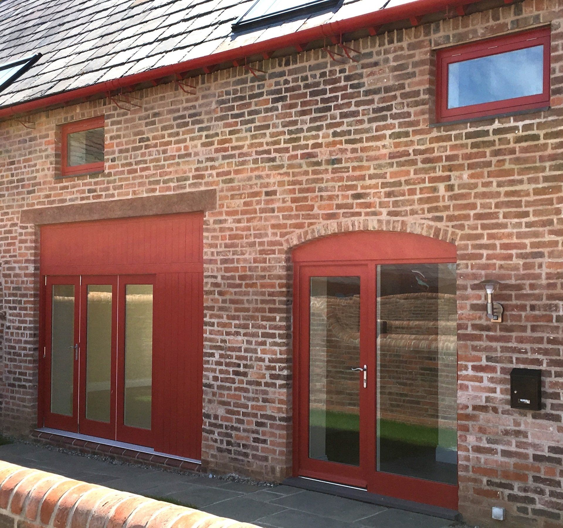 Brick building with red timber door and window frames.