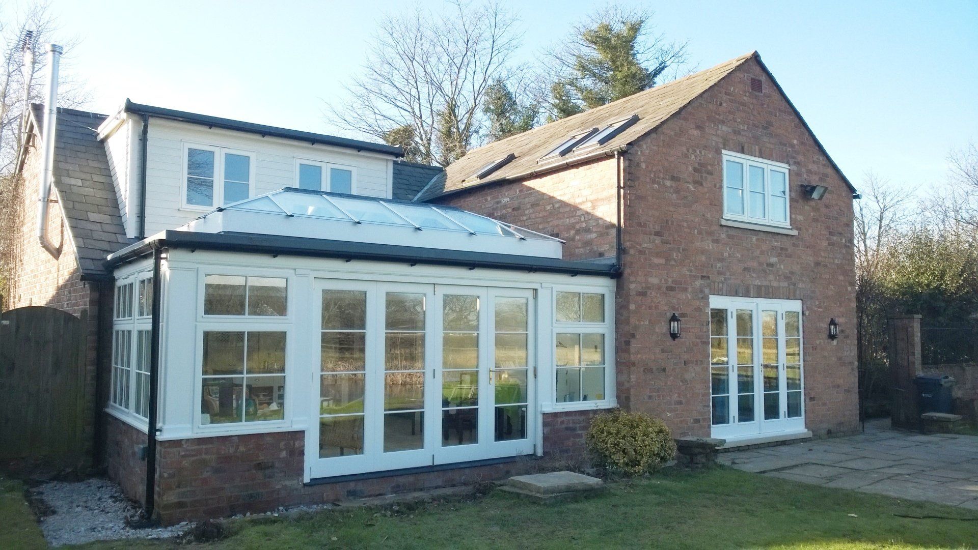 Brick house with white-framed glass doors and windows; sunlit, bright exterior.