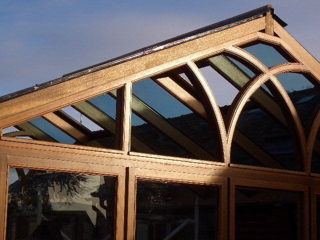 Wooden framed structure with arched glass panels and roof, possibly a conservatory or greenhouse.