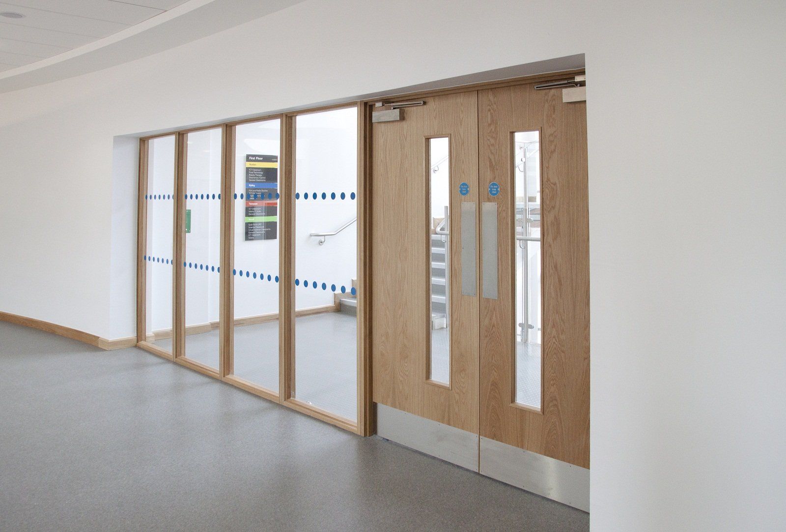 Wooden doors and glass panels in a building hallway.