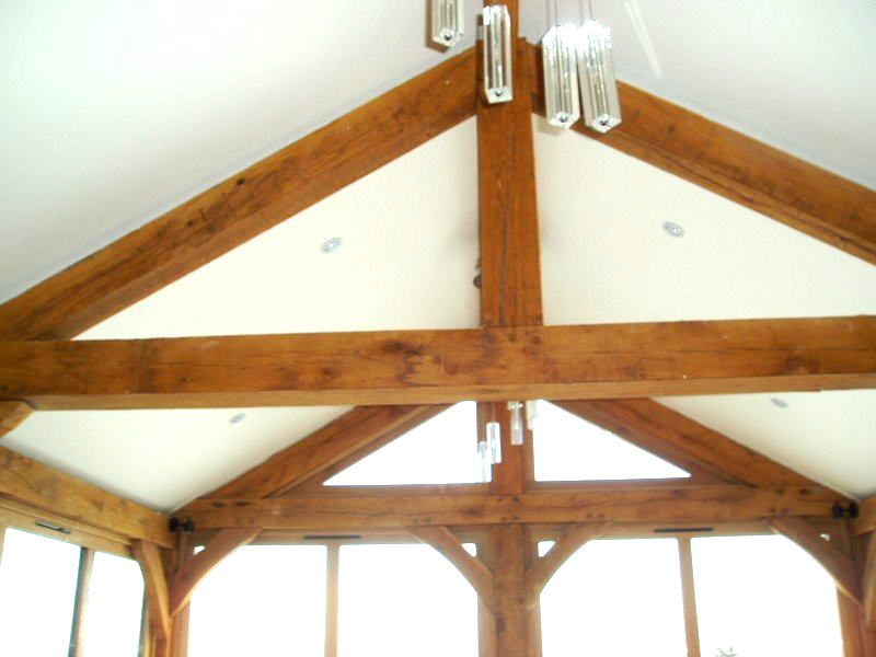 Wooden beams of a vaulted ceiling with a white interior, glass pendant lights.