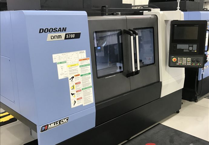 A doosan machine is sitting on the floor in a factory.