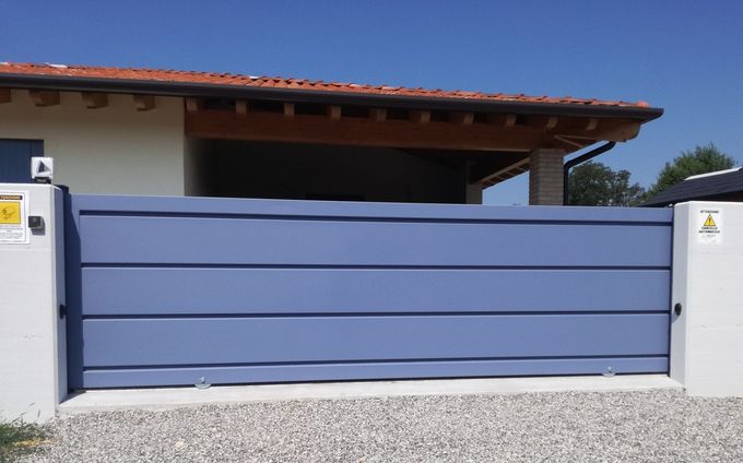 Un cancello scorrevole blu è davanti a una casa