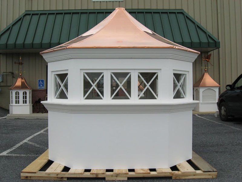 A white building with a copper roof sits on a wooden pallet