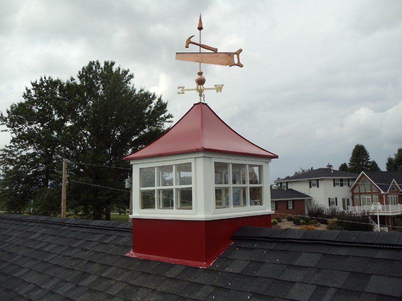 A weather vane on top of a red roof