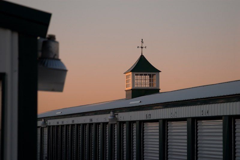 A row of storage units with a weather vane on top of them.