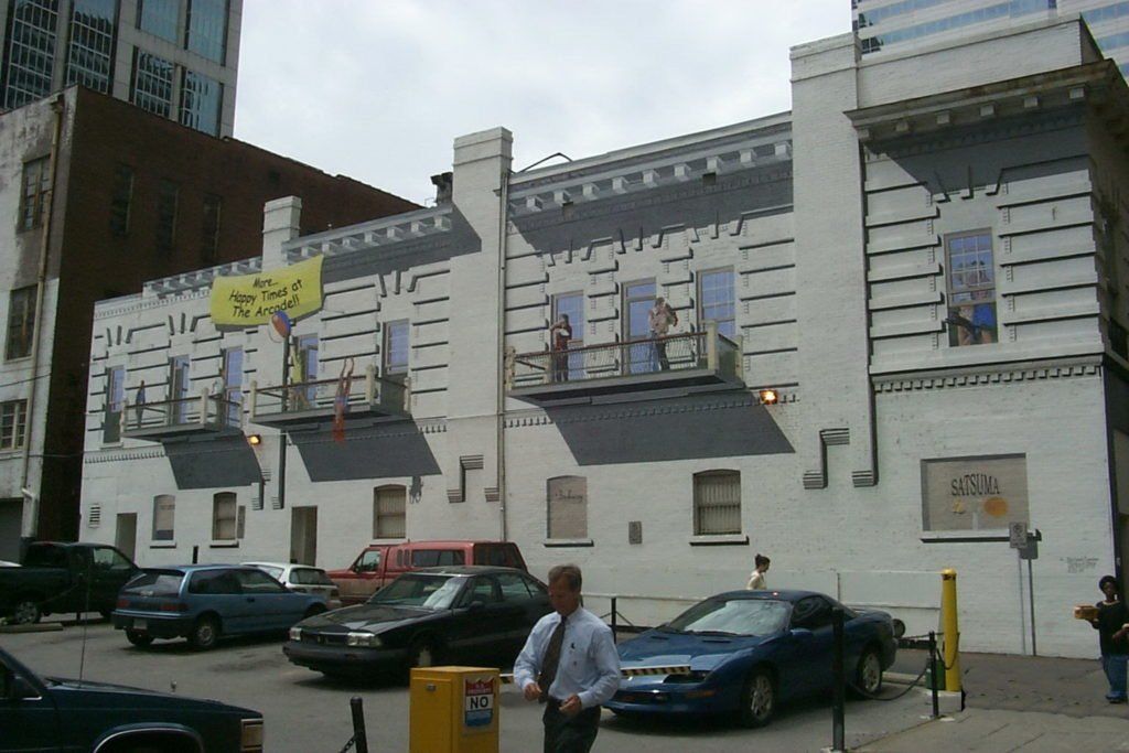 A blue car is parked in front of a white building