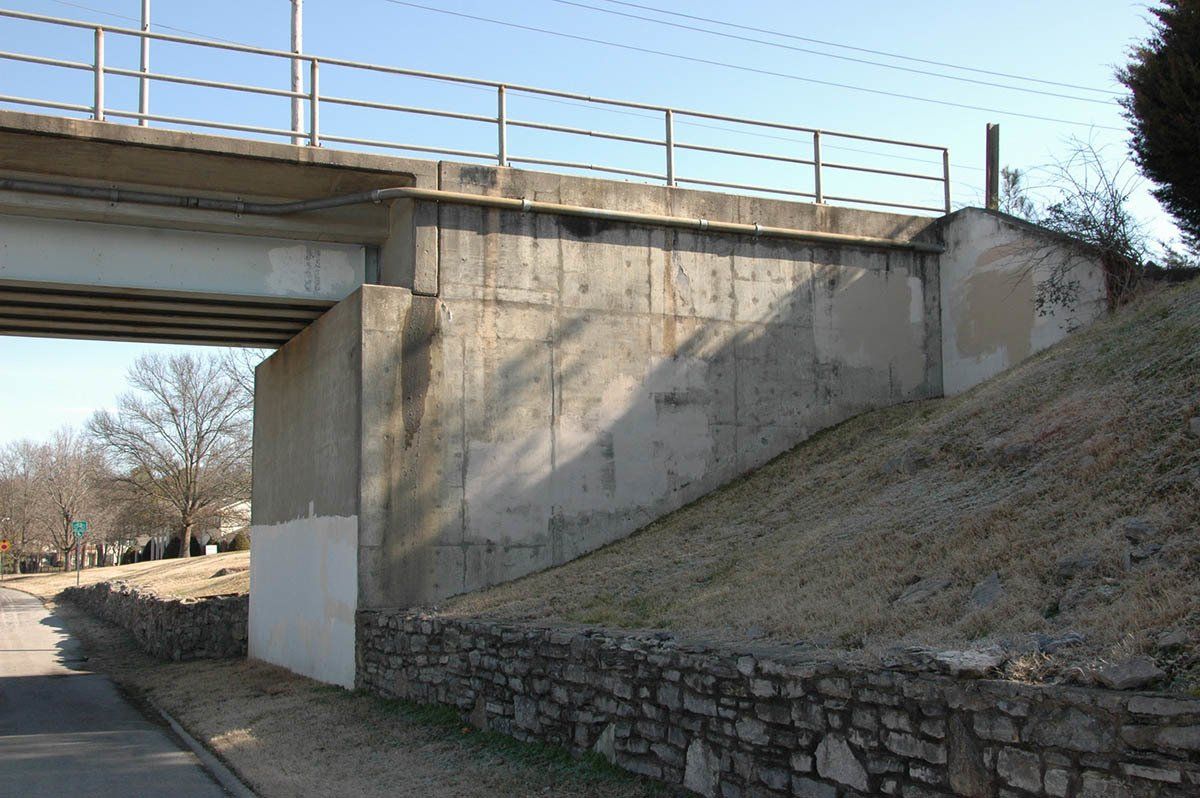 A bridge over a road with a stone wall behind it