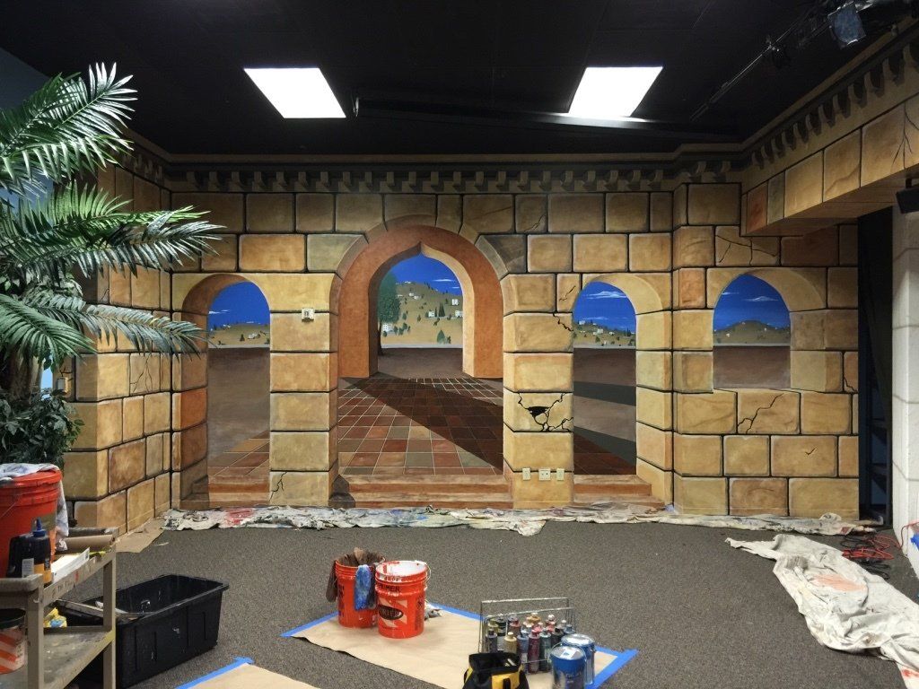 A room with a painting of arches on the wall