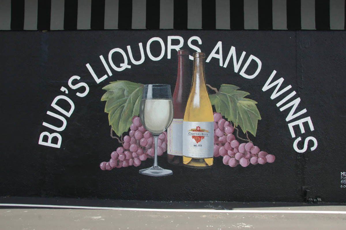 A sign for bud 's liquors and wines with a bottle of wine and a glass of wine
