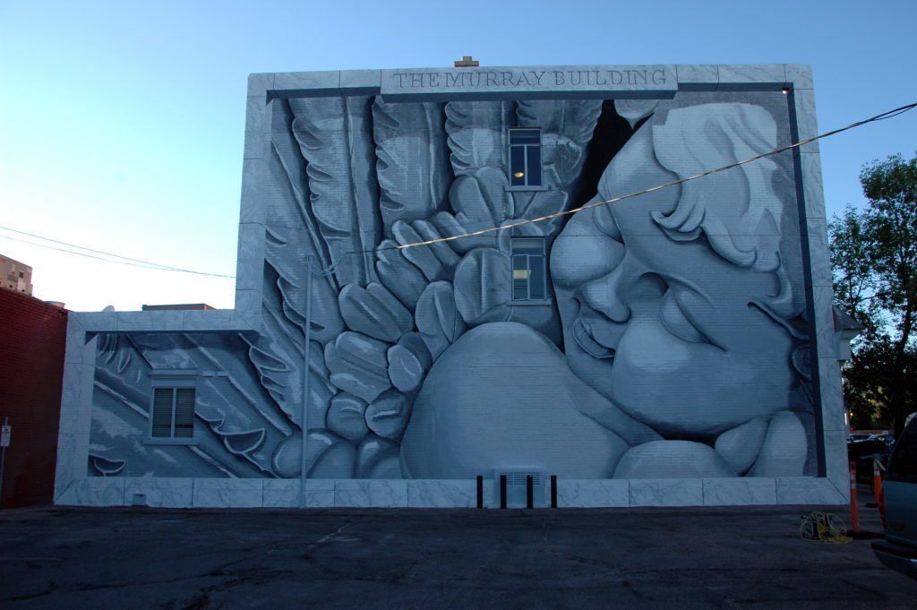 A large mural on the side of a building shows a man and woman hugging