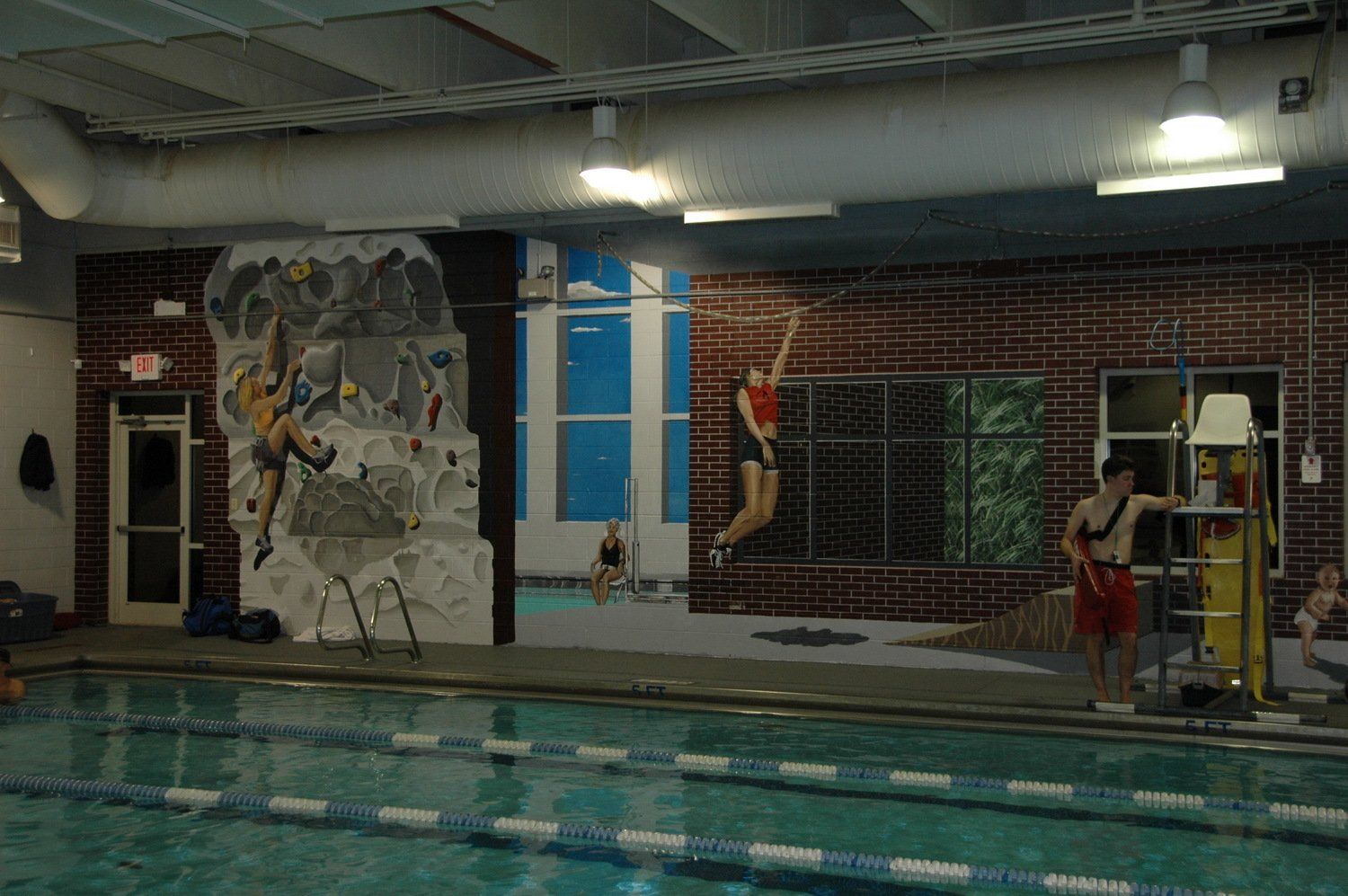 A large indoor swimming pool with a mural on the wall behind it.