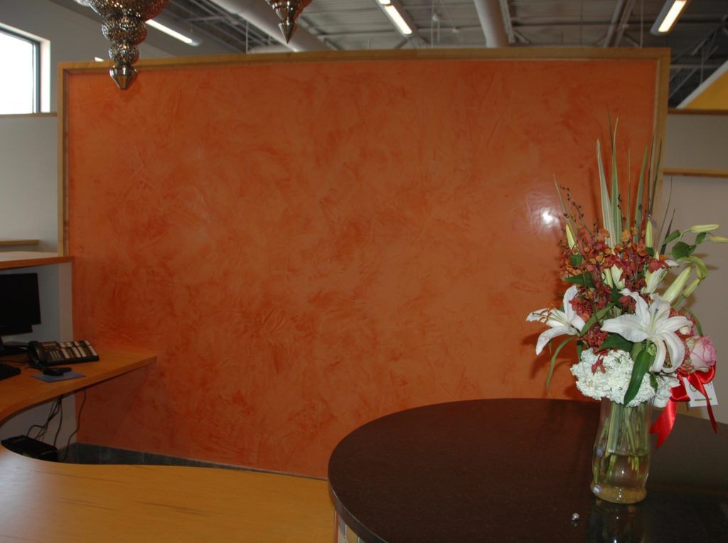 A vase of flowers sits on a table in front of a wall.